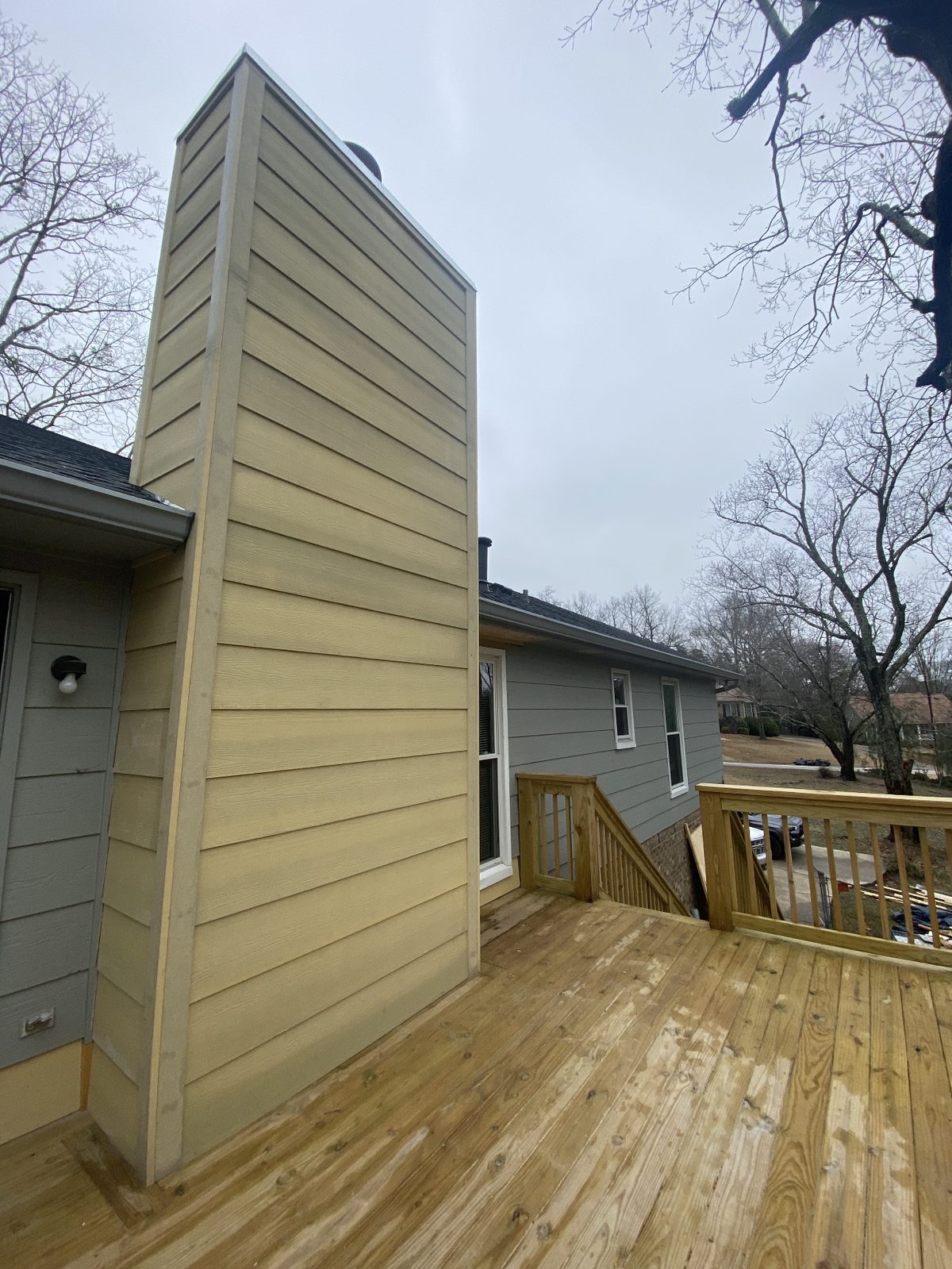 New pressure-treated deck with railings and fresh exterior siding