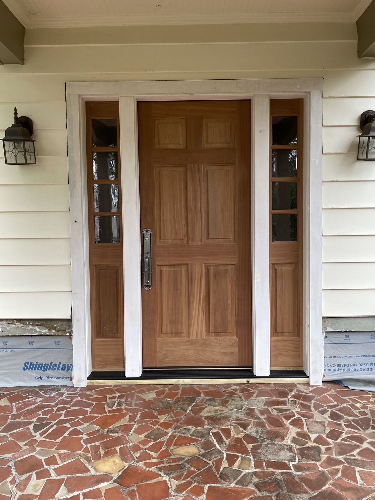 Exterior view of a mahogany entry door with sidelights during installation