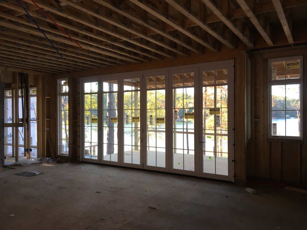 Wall of French doors and windows framed into a lake house overlooking the water
