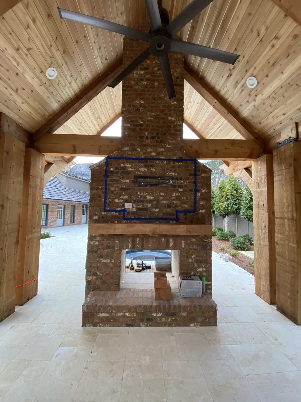Double-sided outdoor brick fireplace under a cedar timber-frame pavilion