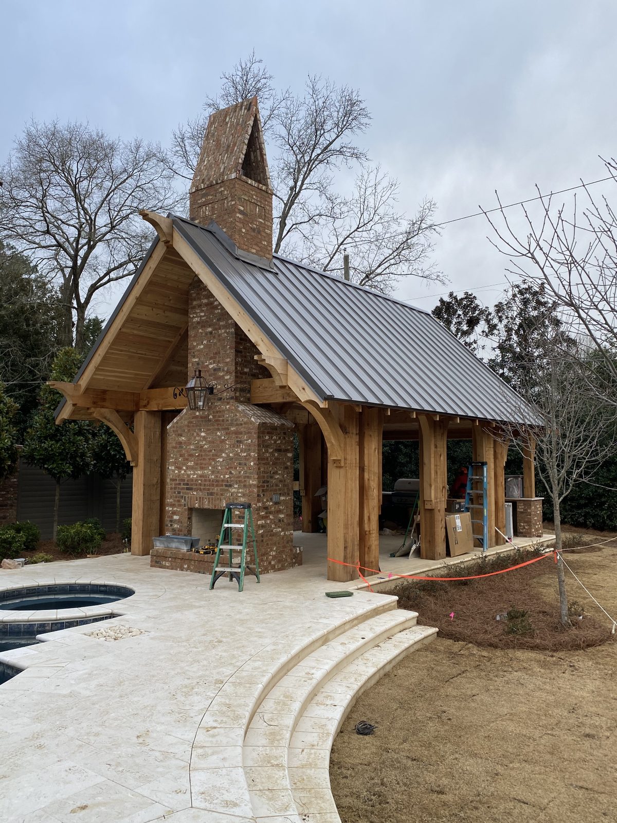 Timber-frame pool pavilion with brick fireplace and standing seam metal roof